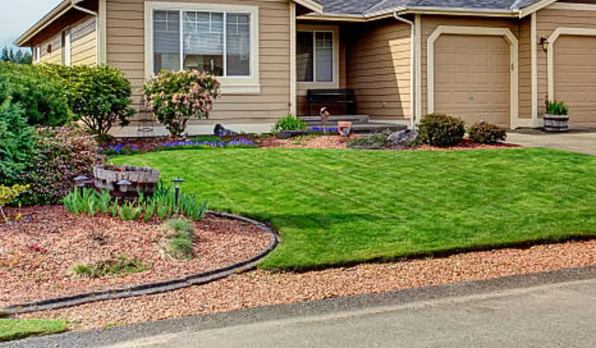 Well-maintained front yard with sloped lawn, gravel edging, and mulched areas to prevent drainage problems near home.