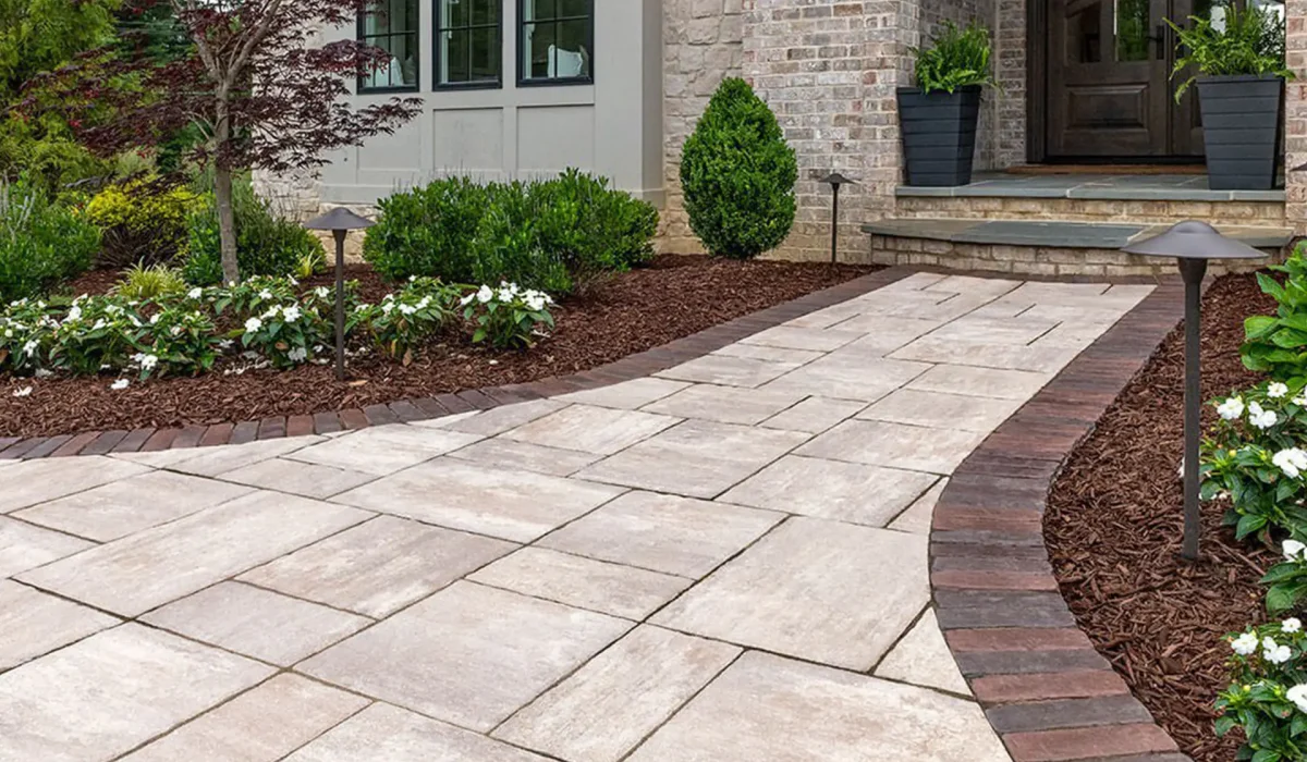 Wide front yard pathway with elegant concrete walkways leading to home entrance, bordered by brick edging.
