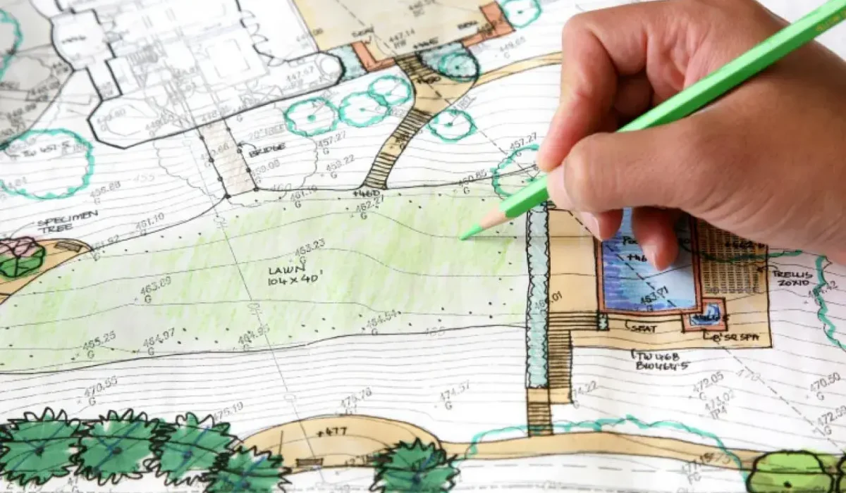 Hand drawing on a landscape plan with green pencil, illustrating creative landscape design ideas.